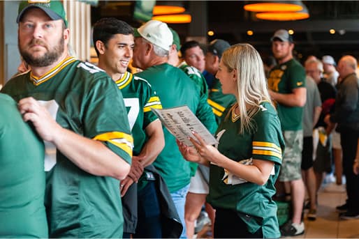 various people standing around wearing green and yellow football jerseys