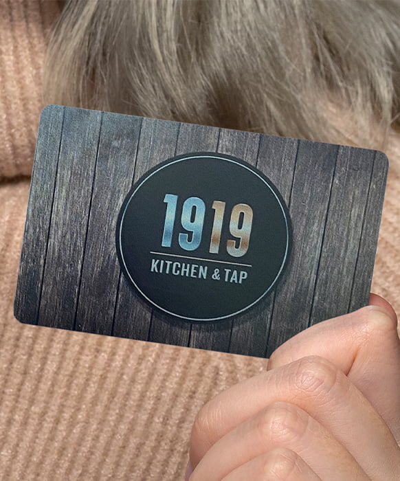 hands holding a mobile phone, on the screen is the 1919 Kitchen & Tap logo displayed along with a message of You've Been Gifted